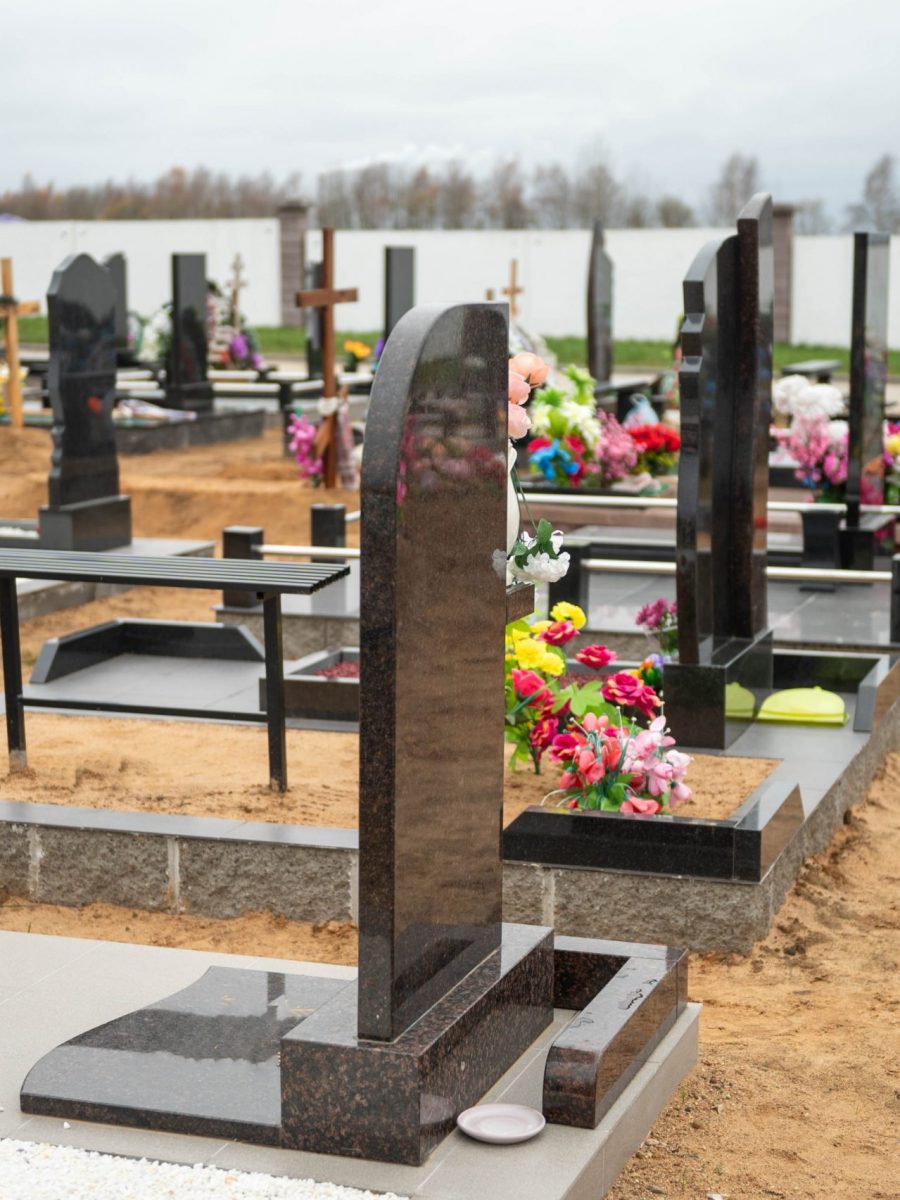 Grave crosses and granite monuments with wreaths in the cemetery on the sand